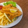 Delicious schnitzel served with crispy french fries, ketchup, and fresh lettuce on a plate.