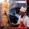 A street vendor skillfully slices doner kebab at a food stall in Istanbul, Türkiye.