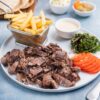 A mouth-watering Middle Eastern shawarma platter with fries and fresh vegetables.